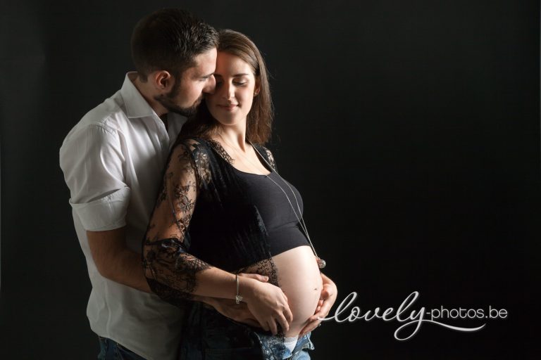 Koppel tegen een zwarte achtergrond: papa omarmt aanstaande mama – zwangerschapsfotoshoot Limburg