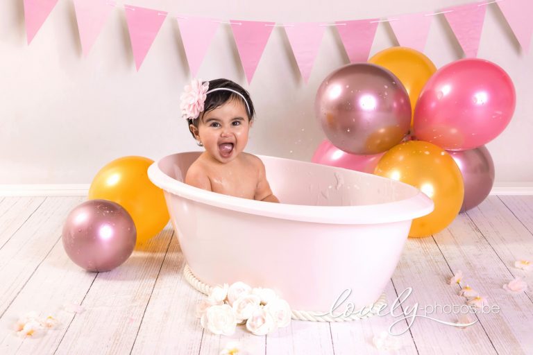 Lachend meisje in een badje met roze en gouden ballonnen – cake smash splash fotoshoot Hasselt