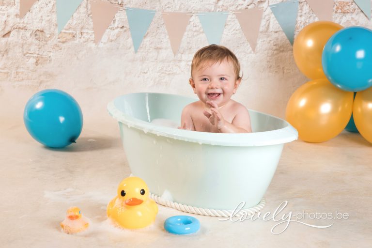 Jongetje in een badje met badeendje en ballonnen na de cake smash – eerste verjaardag fotoshoot