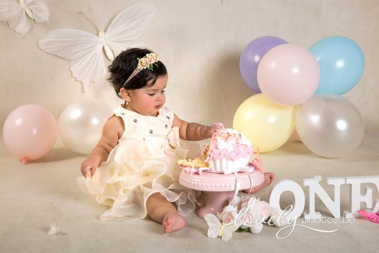 Cake smash fotoshoot Hasselt: meisje met roze taart, pastelballonnen en letters ONE