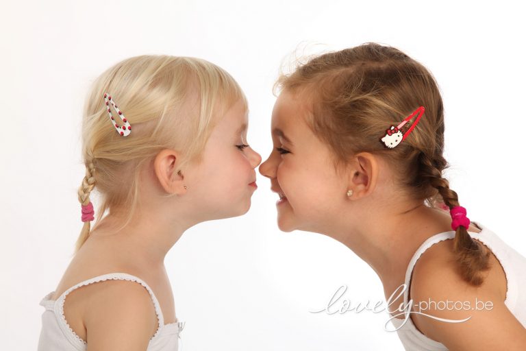 Twee zusjes met vlechtjes geven elkaar een neuskusje – familiefotoshoot Limburg