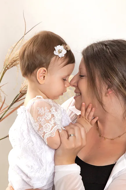 Mama en babydochter neus aan neus in een lichte studio met pampasgras – babyfotoshoot met mama in Hasselt